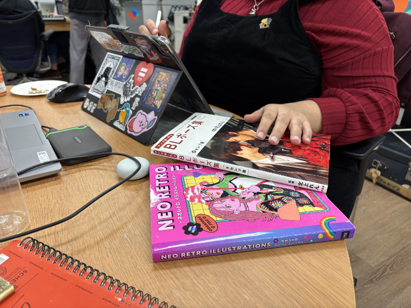 A person's hand resting on "BL Poses" and a "Neo Retro" book.