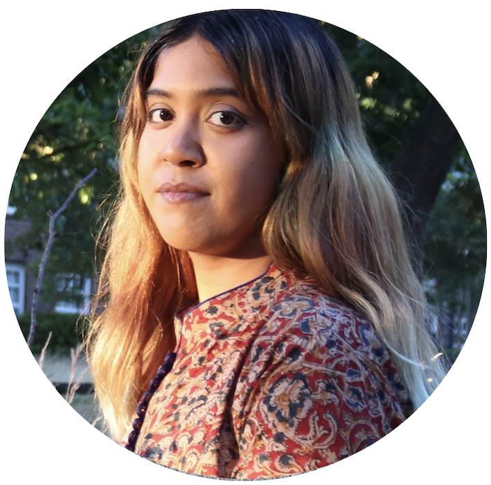 Miranda turns her head to the camera, she is in a street setting with houses and trees