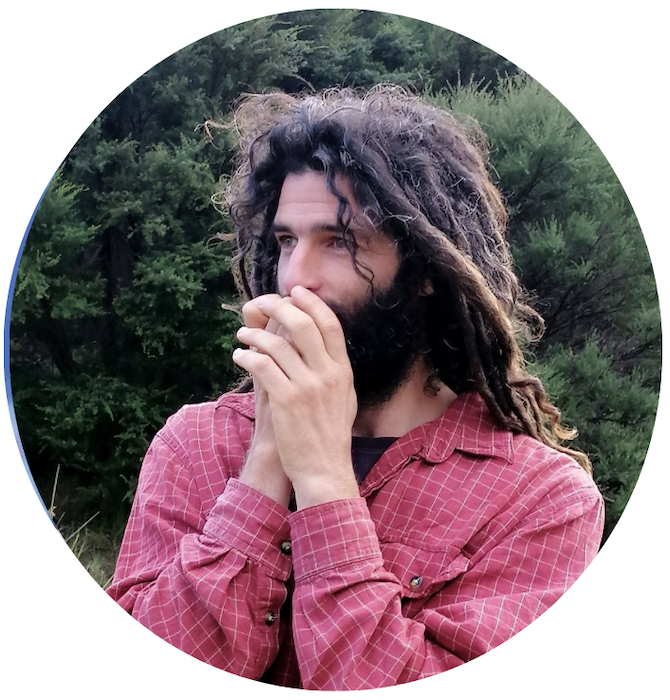 Shaked brings his cupped hands to his mouth. He is outdoors with trees in the background.