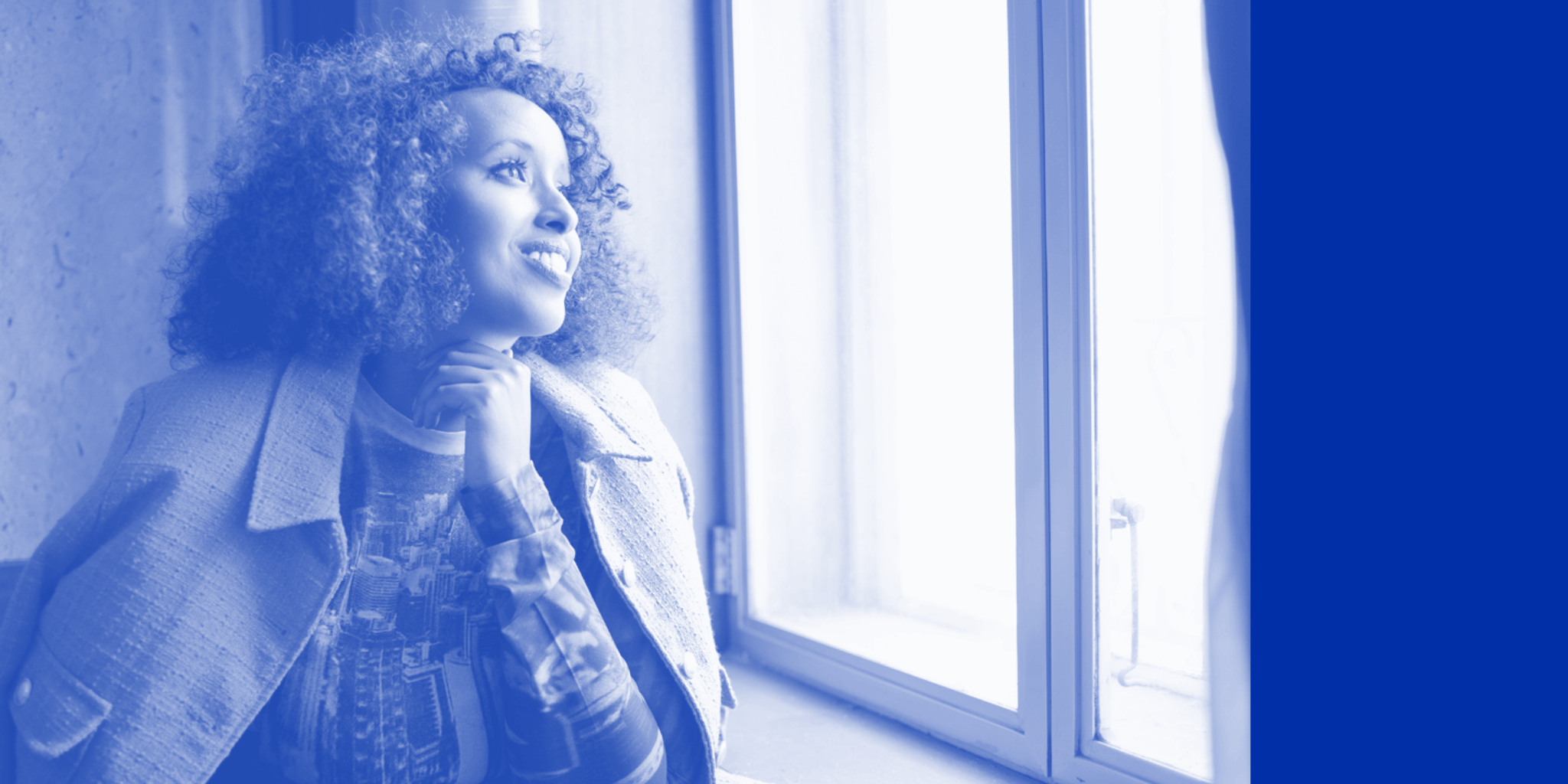 Hedi A black woman with curly hair wearing a business-casual jacket looks optimistically out of a window, in a room with marble walls