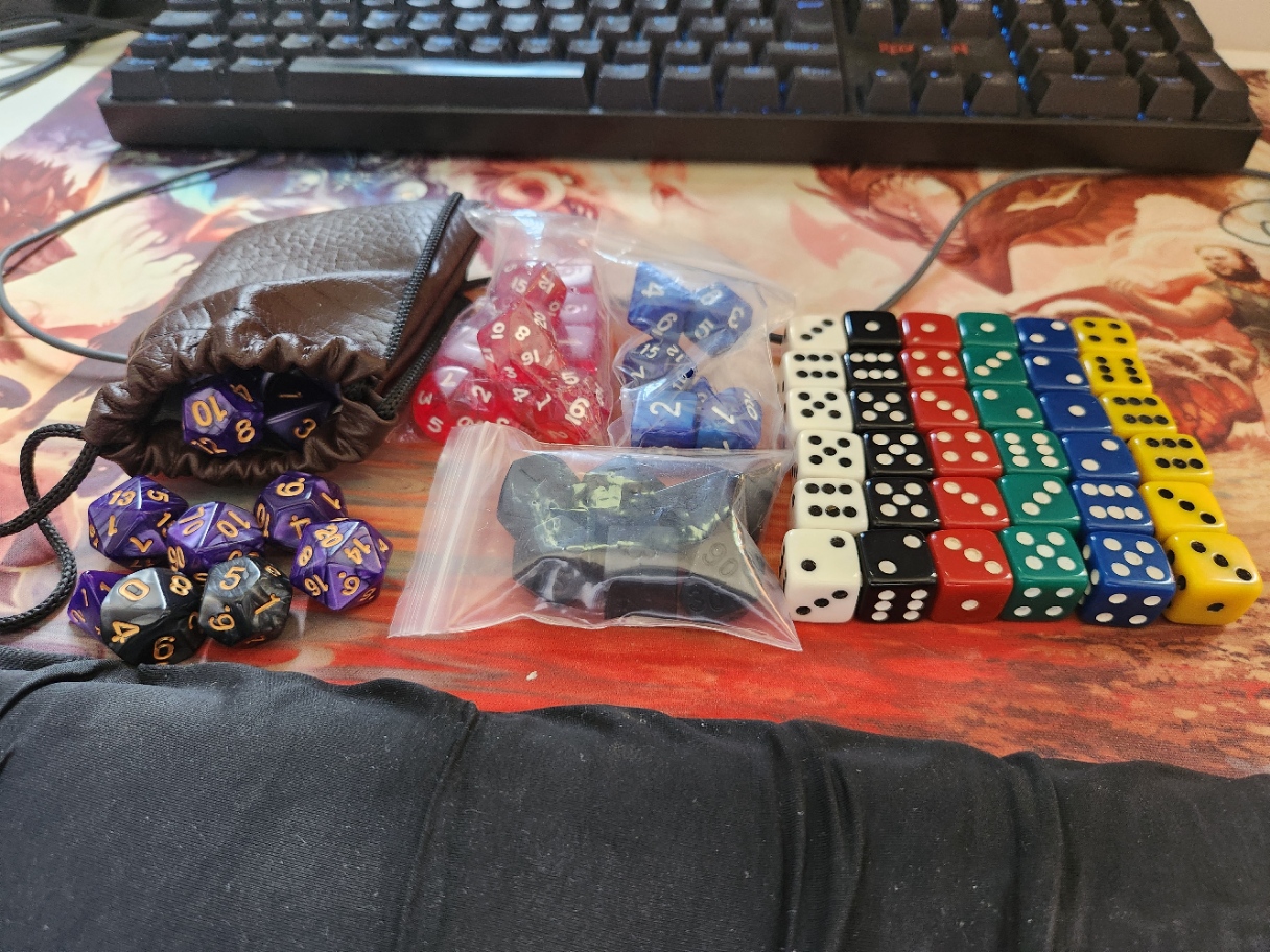 a brown fake leather bag with a few dice coming out of it, three complete sets of dice (one blue, one red and one black) and six sets of six d6, each set with a different color (white, black, red, green, blue and yellow)