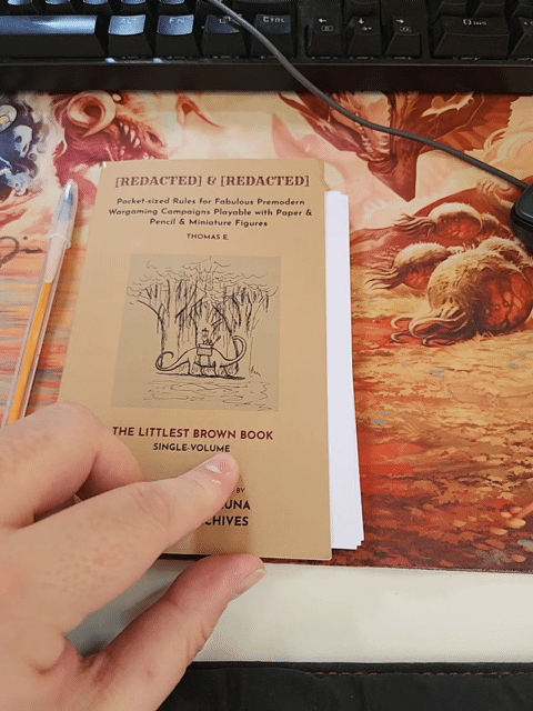 an animated gif showing The Little Brown Book being open showing a pile of index cards inside, with a pen at the side of the book