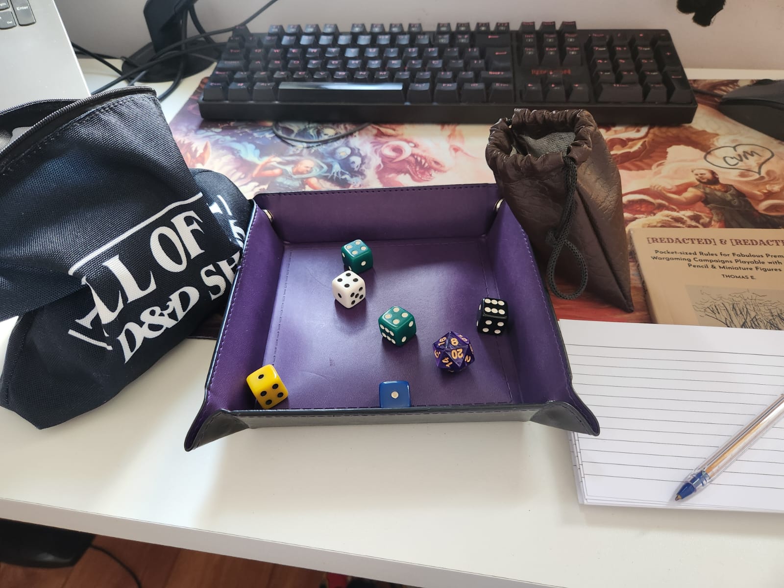 the dice tray mounted with a few dice inside, the black bag on one side, and the brown fake leather bag, The Littlest Brown Book, the index cards and the pen on the other; all set up on top of my desk in front of my keyboard