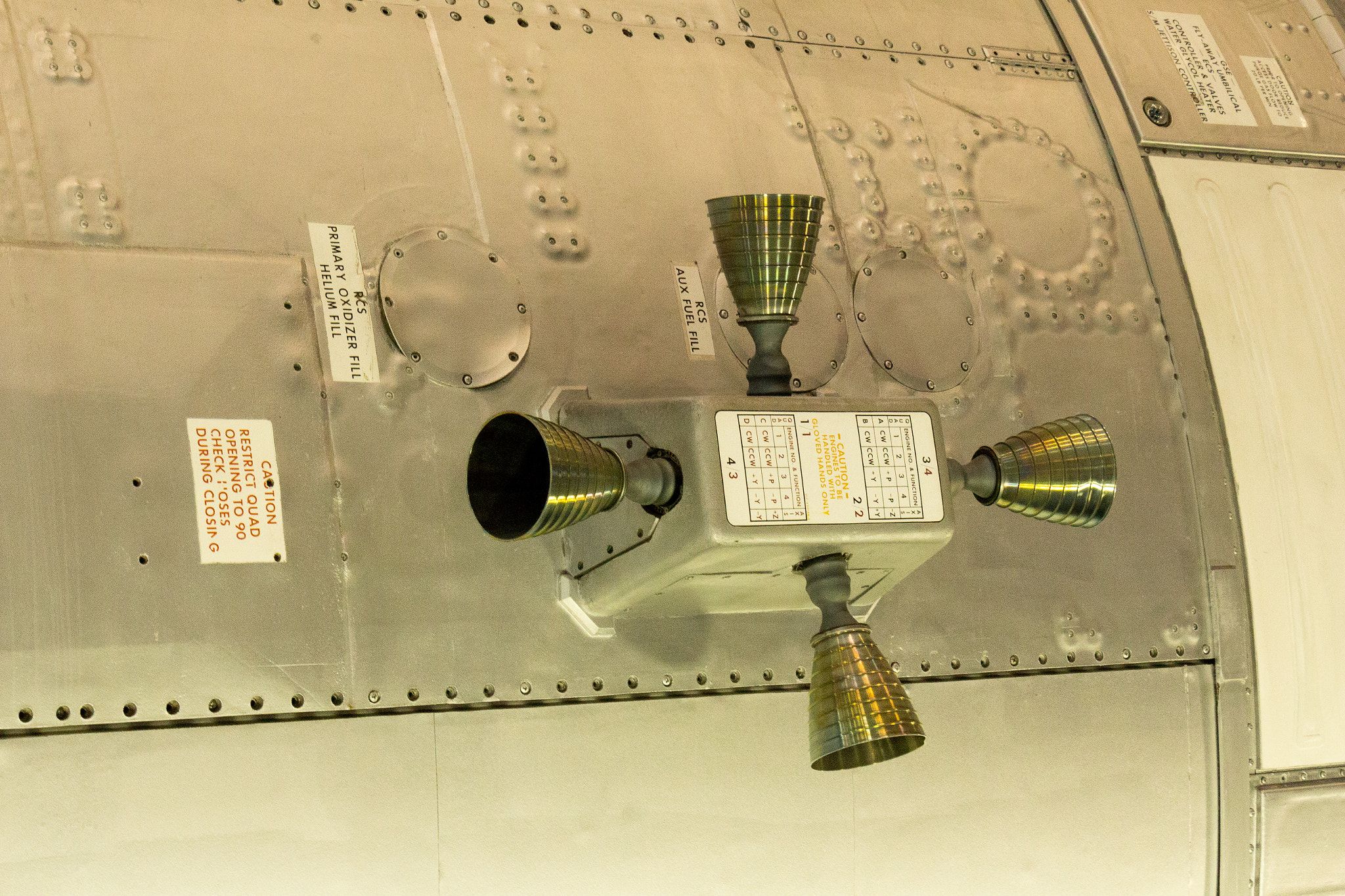 A block on the side of an Appollo module, with four tiny thrusters coming out of the four sides. The one side facing outward doesn't have a thruster, and instead has a sticker with some sort of information about the thruster.